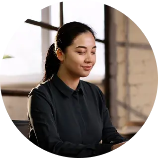 Woman in an office holding a notebook and smiling at the camera.