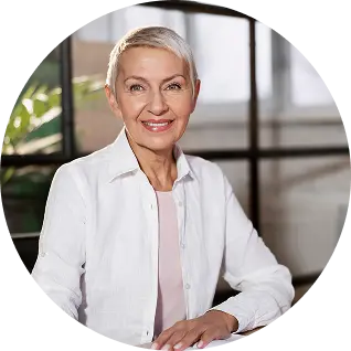 Smiling middle-aged woman with short gray hair wearing a white blouse.